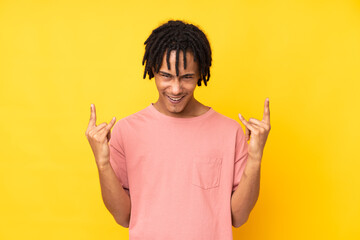 Young african american man isolated on yellow background making rock gesture