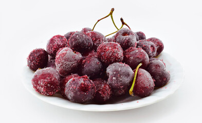Frozen sweet cherries on white plate, cherry in ice crystals.