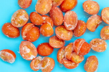 Fozen tomatoes on blue background close-up, concept of preservation of food