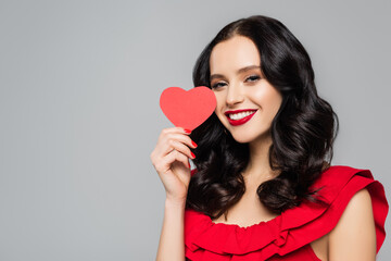 smiling young woman holding red paper heart isolated on grey