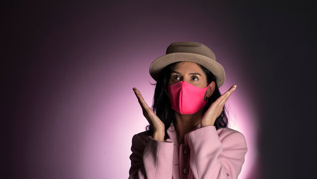 Beautiful woman wearing pink mask. Close-up portrait photo of a young woman with a surgical mask on face. Stay healthy and safe life concept