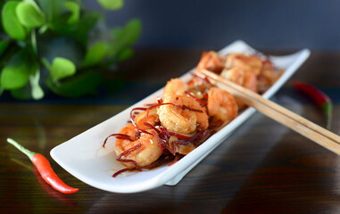 Selective focus of grilled shrimp with onions and chili on a white plate on the table. For asian food menu