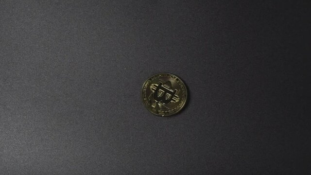 Close-Up of Gold Bitcoin drop and spin on black background floor