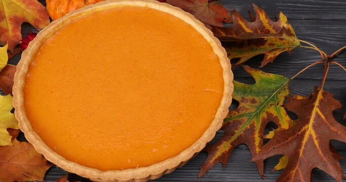 Tasty pumpkin pie and autumn leaves on wooden table