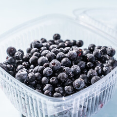Close up on fresh blueberries in plastic box frozen and ready to eat - organic food healthy eating concept