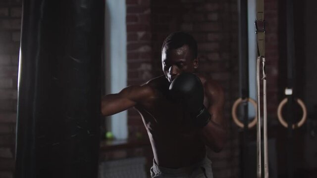 Gym training - a black handsome man punching the punching bag