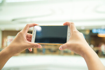 female hand holding a phone on a shopping mall.