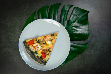 Slice of black dough chicken pizza on plate. Fast food dish on dark stone background. Piece of meat...
