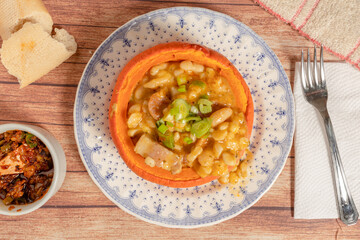 Classic typical food from Argentina and South America, Locro, served in a pumpkin cooked on a vintage plate. Accompanied by the hot sauce. Overhead view