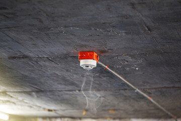 Smoke detector on precast concrete ceiling. Close up of smoke detector for fire protection systems. Selective focus.