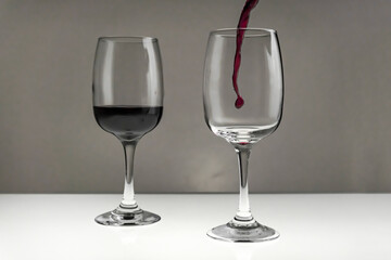 Red wine is poured from a bottle into a glass on a blurred background, close-up.
