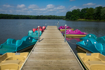 Paddleboats surround a dock on a lake.