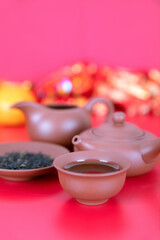 Tea cup, tea set and tea leaves on red background