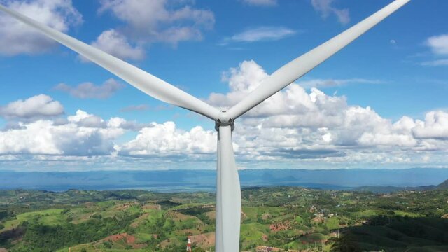 Aerial view of Powerful wind turbine farm for alternative energy production on clouds blue sky warm summer at highland. Cenerating clean renewable energy for sustainable development
