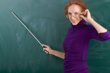 Teacher standing at blackboard with pointer