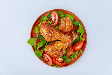 Roasted spicy chicken drumstick with salad on white background.