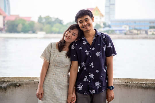 Asian Couple standing by the river to take pictures.