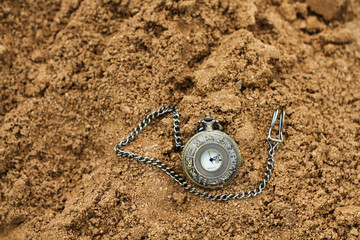 a vintage pocket watch on brown sand