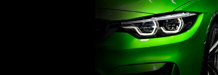 Close up detail green modern car headlights with led technology on black background free space on...