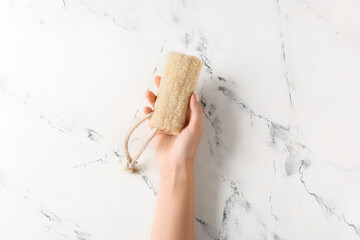 Female hand with loofah on light background - obrazy, fototapety, plakaty