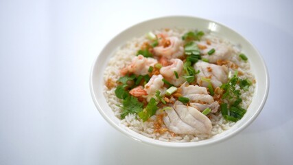 Boiled rice soup with fish and shrimp in bowl on wood white background