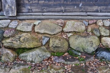 The wall of an old wooden house on a stone foundation. Rock Wall Foundation.