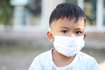 Asia boy wearing facial mask for protect corona virus and air pollution pm2.5 with blurred background. Wuhan coronavirus. Covid-19, pm2.5 and health care concept.