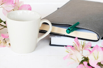 notebook planner for business with bougainvillea pink flower and cup coffee arrangement flat lay style  on table white at office 