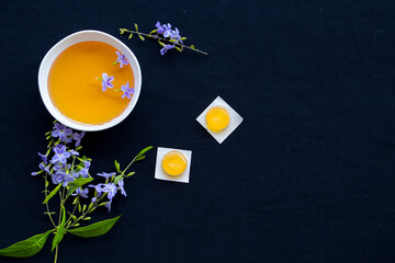 Fototapeta na wymiar cough sore throat pastille pills from herbal honey and lemon with purple flowers arrangement flat lay style on background black