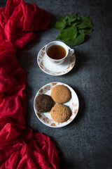 Top view of a cup of tea and a plate of cookies on a background with use of selective focus.