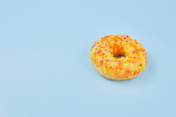 Donuts glazed with sprinkles on pastel blue background. Sweet doughnuts on blue paper.