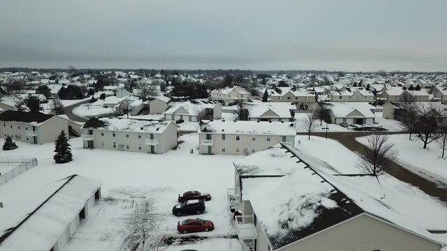 Aerial drone video of a suburban neighborhood covered in snow during winter.