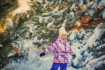 Portrait of a happy little girl on a winter walk . A child in comfortable clothes in the forest