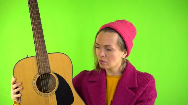 Crazy Woman with Strange Look, Pink Comb Combing Guitar, Surrealism on Green Background. Psychopath, Guitar Tuning, Advertising Concept.