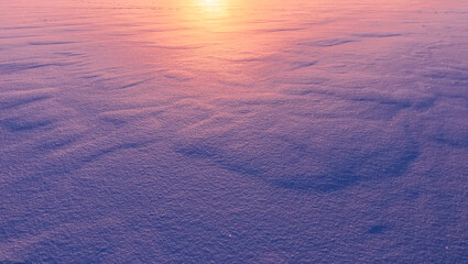 beautiful blue and purple colored snow field surface illuminated by evening sunset , violet snow texture , original winter background