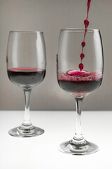 Red wine is poured from a bottle into a glass on a blurred background, close-up.