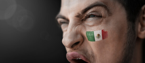 A screaming man with the image of the Mexico national flag on his face
