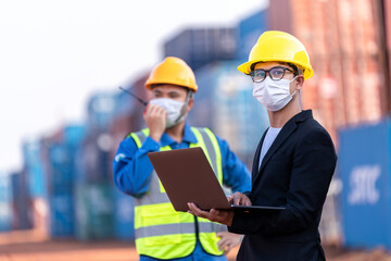 Asian male logistic warehouse foreman with worker using laptop checking list planning and strategy of container boxes from cargo freight ship. industry import export shipping business.