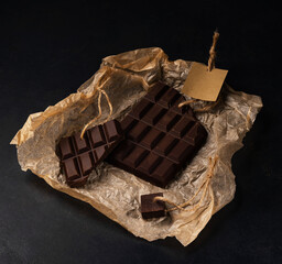 pieces of dark chocolate with tag on paper on dark background