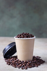Takeaway coffee cup and roasted coffee beans, light concrete background. Coffee shop concept.