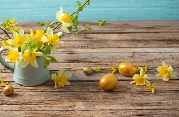 Golden Easter eggs and yellow flowers on wooden background