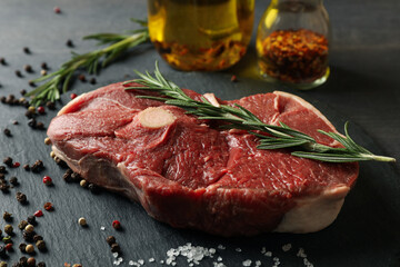 Tray with steak meat with herbs and spices on dark table