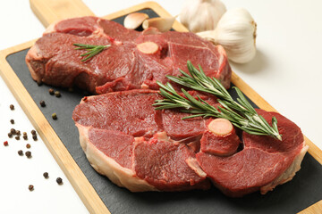 Board with steak meat, herbs and spices on white background