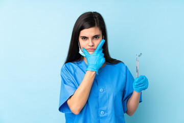 Young woman dentist holding tools over isolated blue background thinking an idea