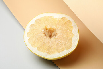Slice of ripe pomelo fruit on three tone background