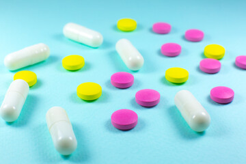 Colored pills and tablets on green background. Close up. Medical treatment concept.