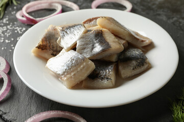 Black tray with plate of fresh herring fish slices
