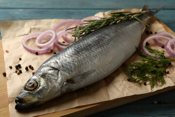 Board with fresh herring fish and spices on wooden background