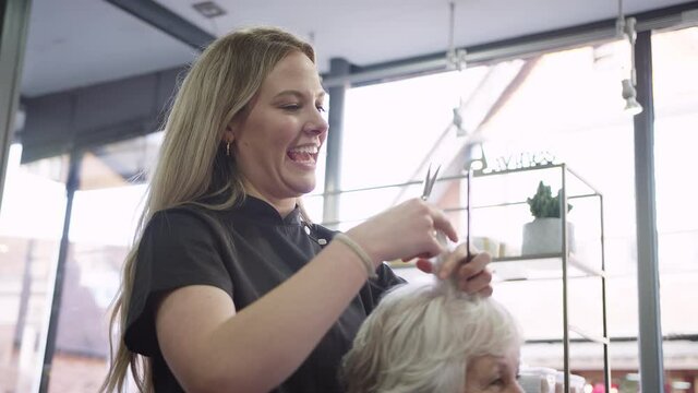 Senior Woman Having Hair Cut By Female Stylist In Hairdressing Salon