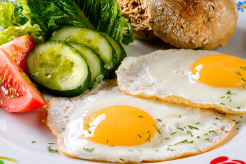 Two fried eggs serve with roasted vegetables and bacon, closeup fried egg with vegetables for...